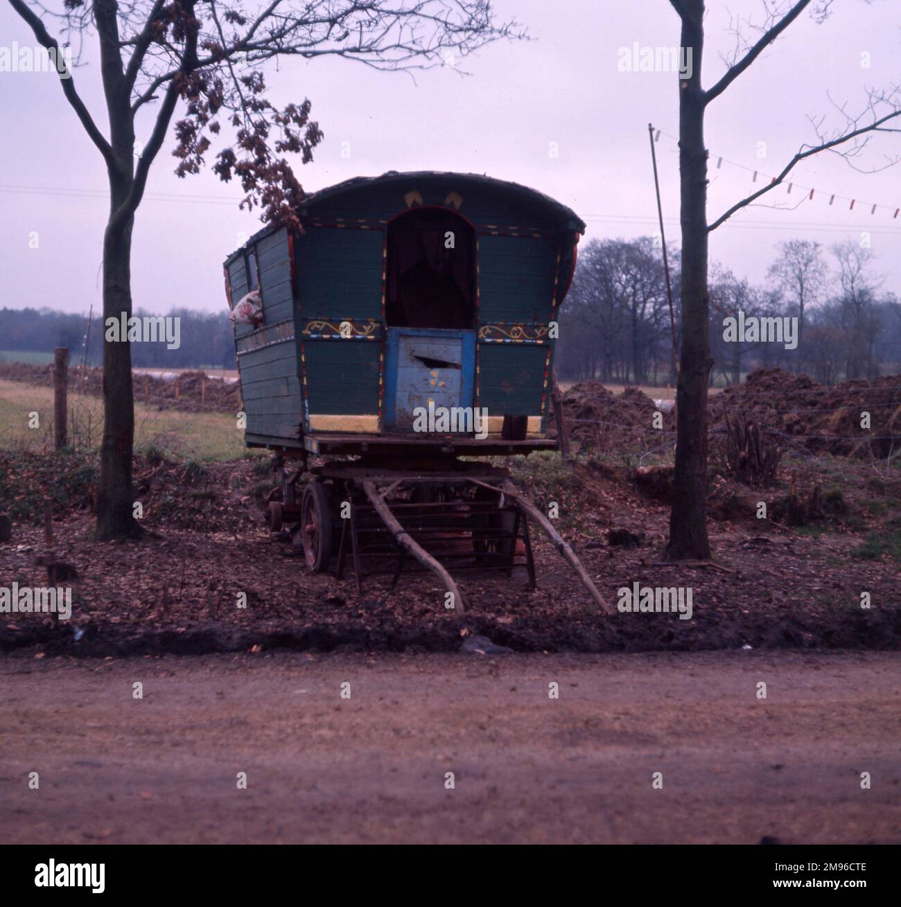 Une caravane gitane verte sur le côté de la route, peinte en vert avec des décorations rouges et jaunes, et une porte bleue. Banque D'Images