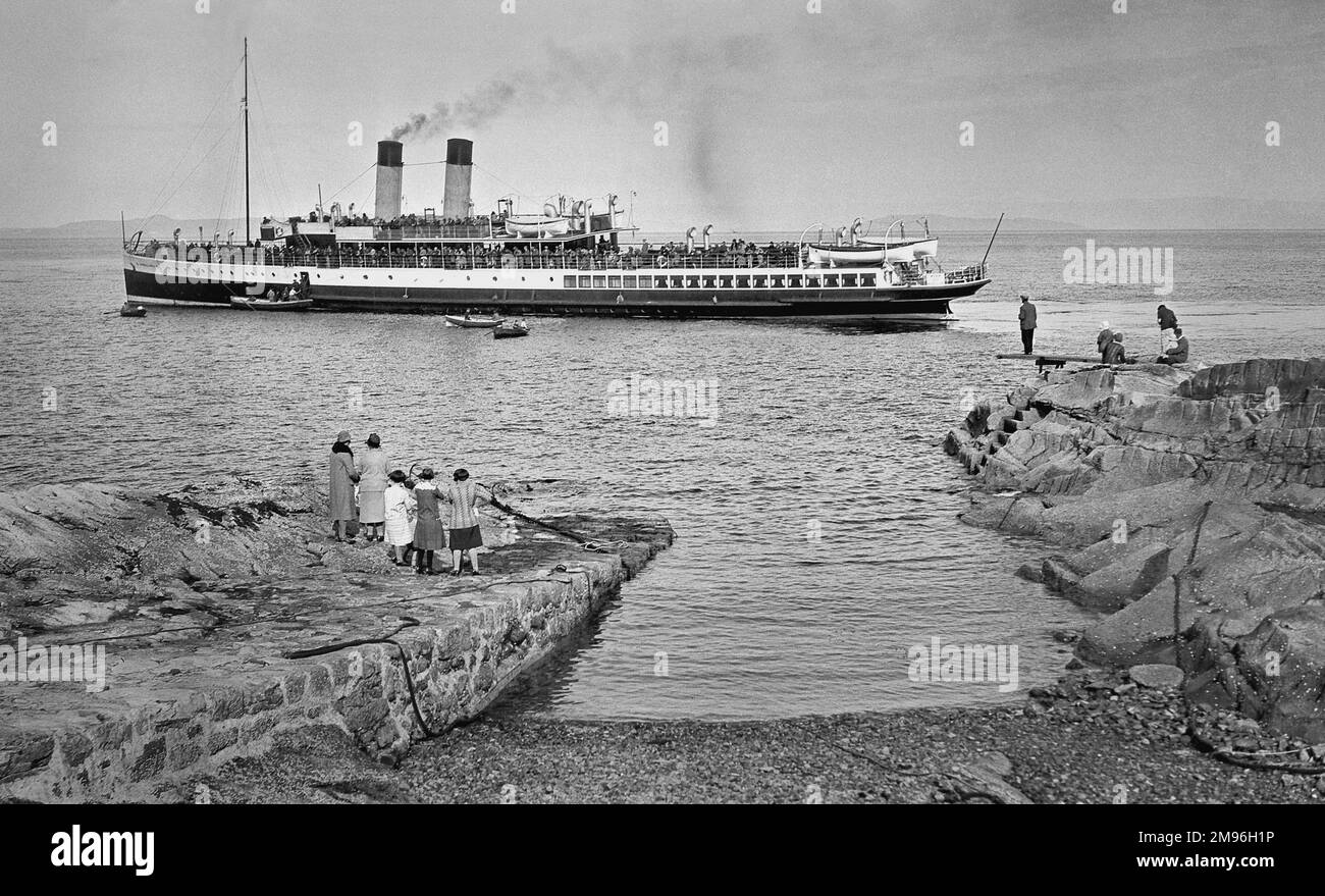 Des gens debout sur une jetée, regardant un bateau à vapeur. Banque D'Images