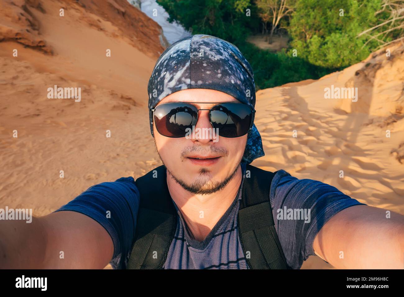 Homme randonnée avec un sac à dos fait un selfie sur le visage de  l'appareil photo dans des lunettes de soleil et un bandana dans le voyage  Photo Stock - Alamy