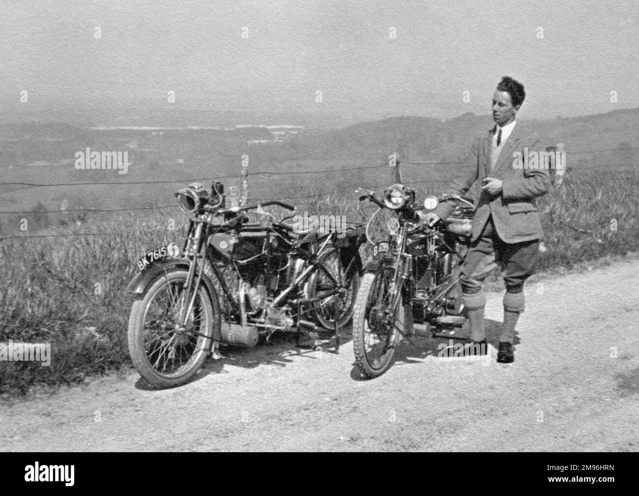 Homme debout sur une voie de campagne avec deux motos. Banque D'Images