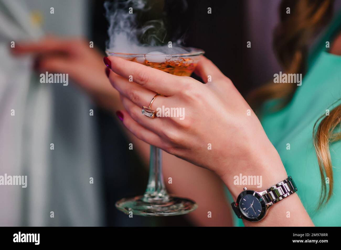 Main de femme avec un verre Martini avec des bulles et de la vapeur gros plan Banque D'Images