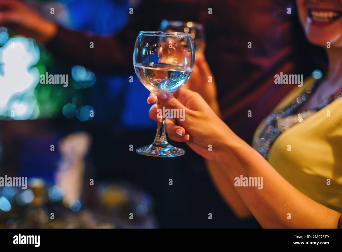 des verres de vin blanc dans la main d'une femme heureuse en gros plan Banque D'Images