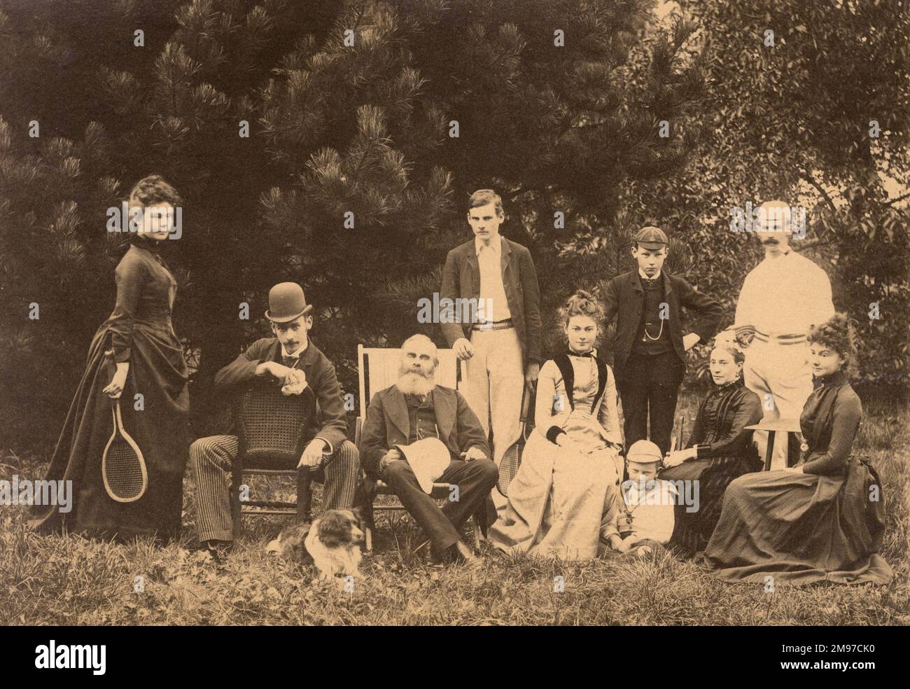 Un groupe de famille, avec une partie de la fête vêtue d'une tenue de sport. La femme à gauche tient une raquette de tennis. Banque D'Images