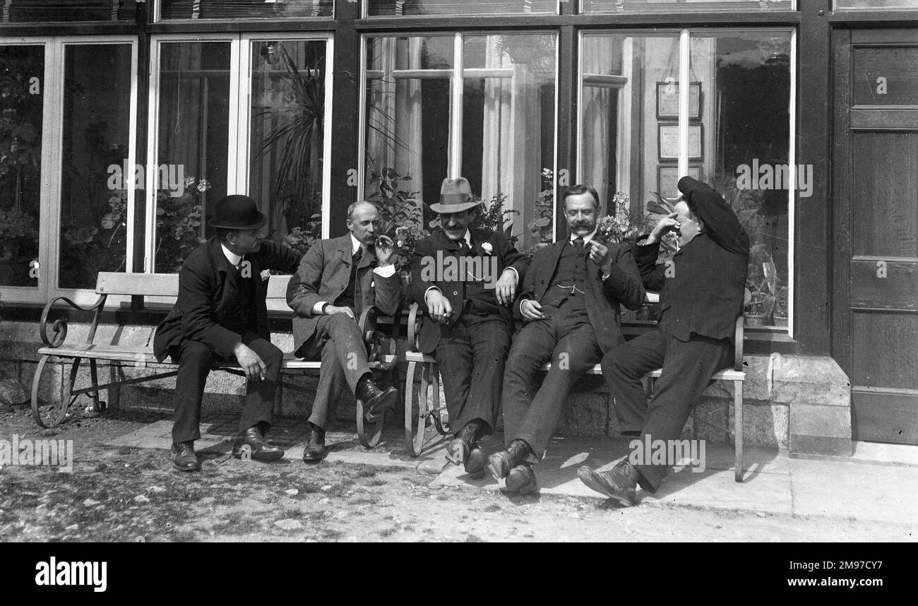 Groupe d'hommes en conversation à l'extérieur du club de tennis House - une photo charmante qui capture une scène très naturelle et détendue avec compassion et humour Banque D'Images