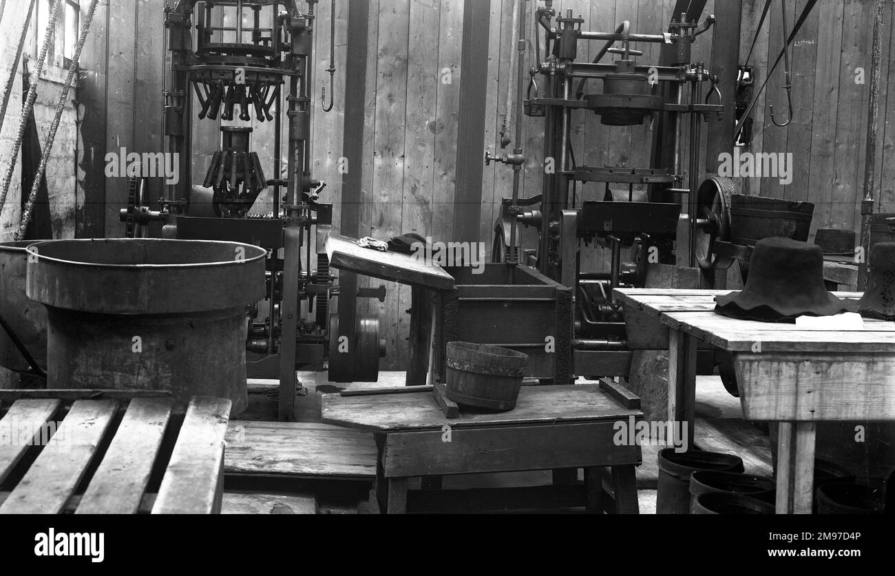 Blocking shop à Battersby's Hatworks - le chapeau feutre sur la droite attend encore plus de formation. Noter l'entraînement par chaîne massif sur la machine sur la gauche. Banque D'Images