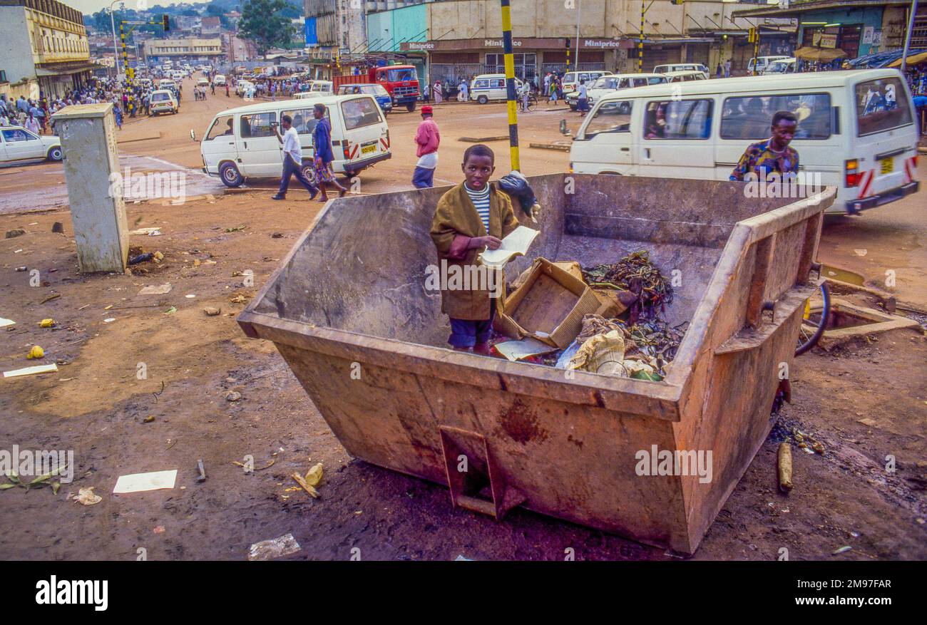 Ouganda, Kampala, enfant de la rue à la recherche de nourriture dans un conteneur de déchets. Banque D'Images