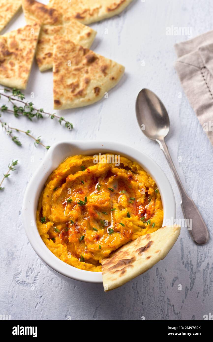 Délicieux houmous aux haricots maison avec citrouille cuite, tahina et épices avec pain plat sur fond bleu clair, vue du dessus Banque D'Images