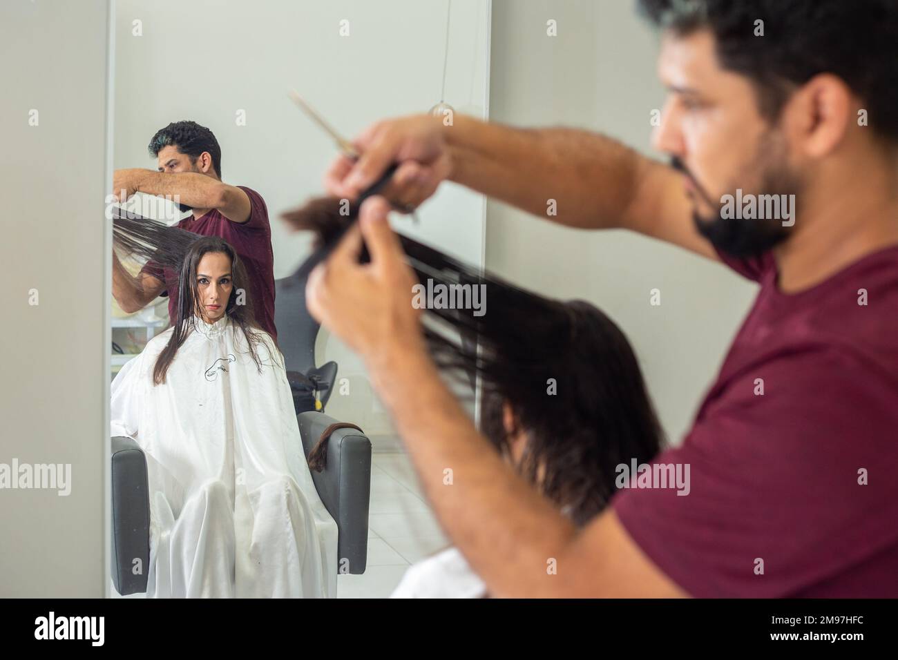 Goiania, Goiás, Brésil – 10 janvier 2023: Détail d'un coiffeur séparant une serrure de cheveux d'un client à couper. Banque D'Images