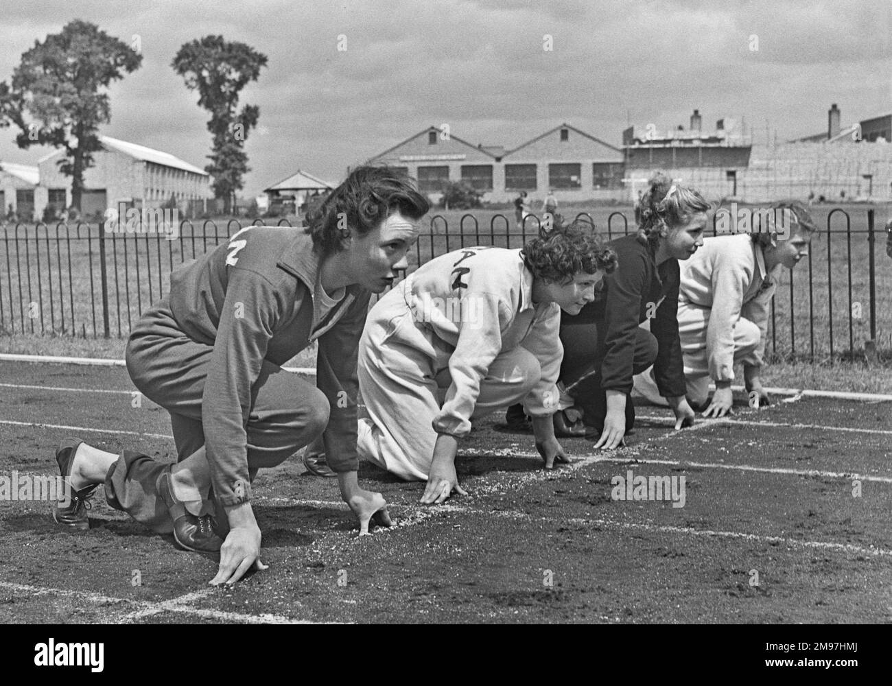 Quatre athlètes féminins sur la ligne de départ d'une piste sportive. Banque D'Images