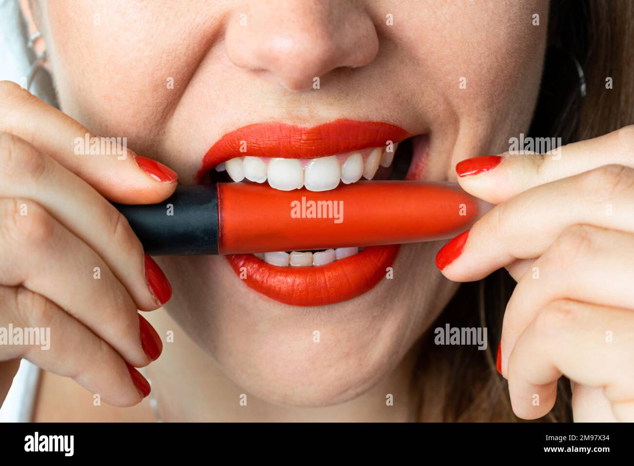 Gros plan sur la bouche d'une femme qui mord un rouge à lèvres Banque D'Images