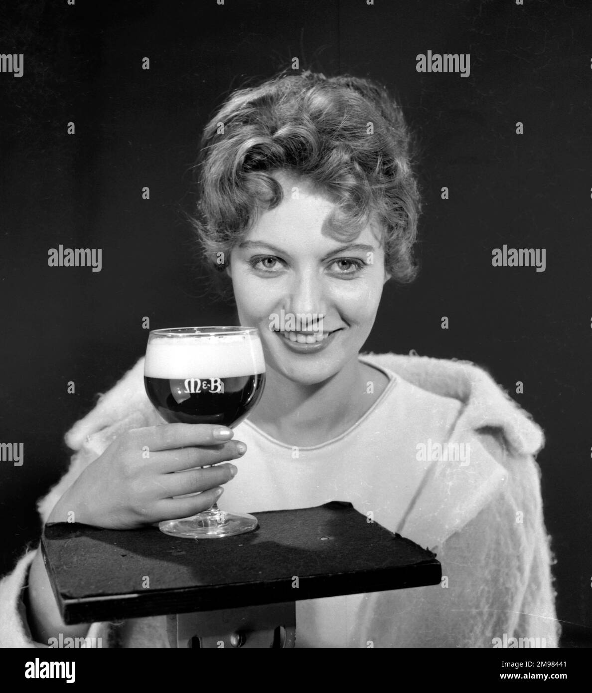 Publicité pour M&B Amber Beer -- modèle féminin (Gillian Watt) tenant un verre. Banque D'Images