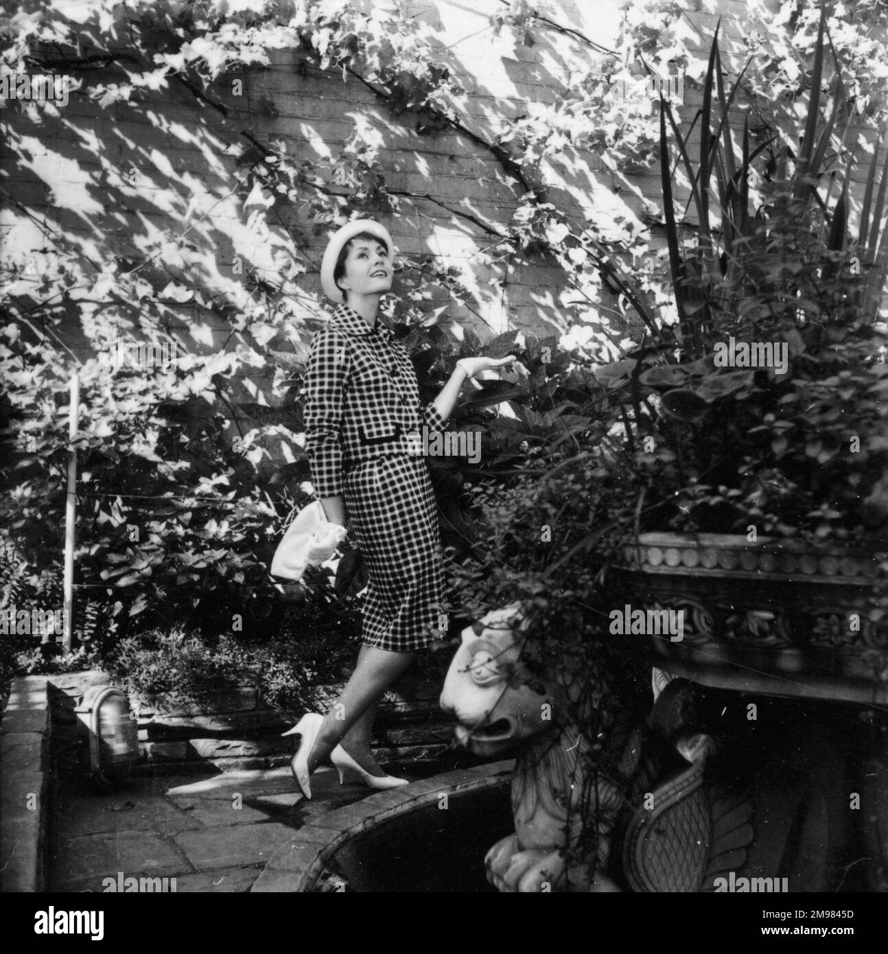 Jeune femme (modèle - Geraldine Hill) à modeler un costume dans un jardin. Banque D'Images