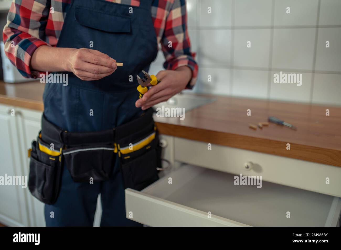 Photo rognée d'un militaire tenant une pince et une cheville en bois dans les mains Banque D'Images