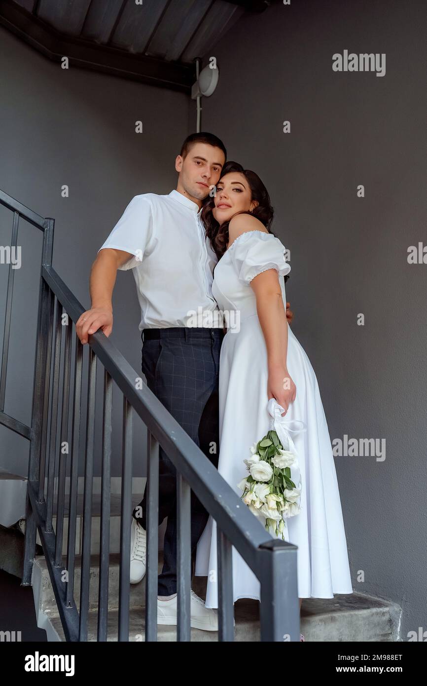 Bonne nouvelle. Une fille à cheveux noirs s'est accroché doucement à son futur mari sur un vieux escalier en fer dans un entrepôt Banque D'Images