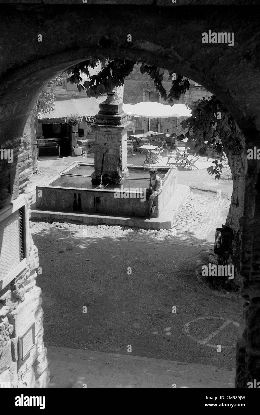 Place avec garçon assis à une fontaine en Provence, sud-est de la France. Banque D'Images