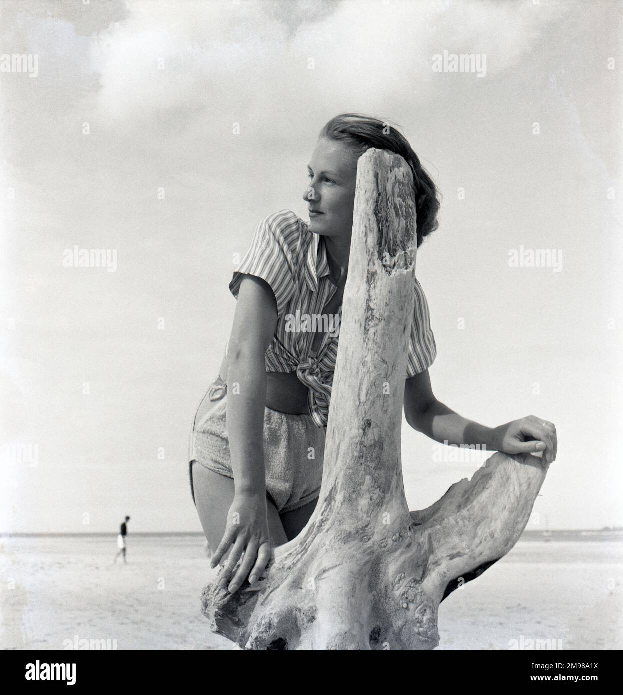 Femme sur la plage avec du bois flotté -- l'une des images prises par Adams pour la campagne britannique d'après-guerre en temps de paix. Banque D'Images