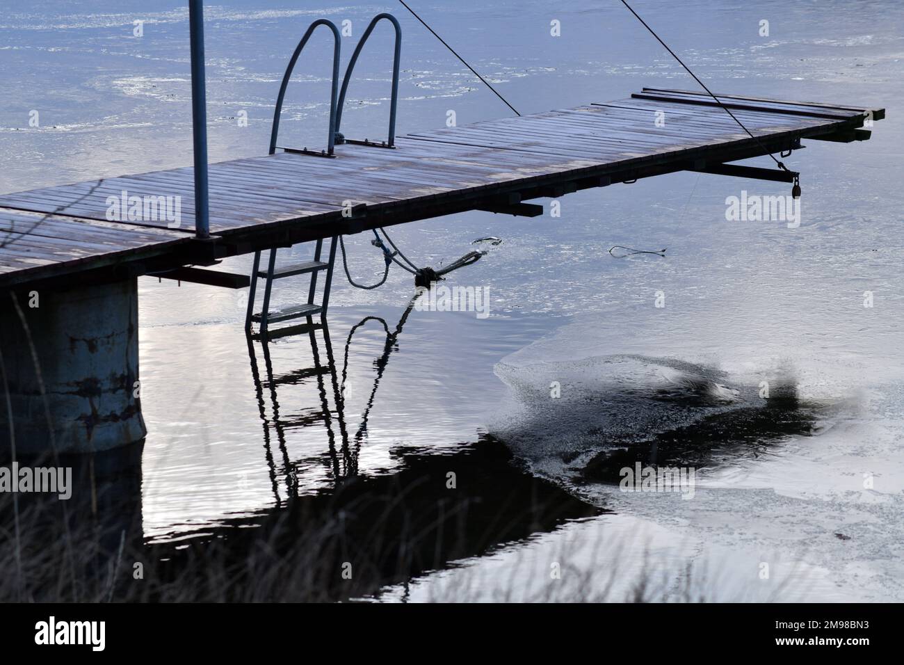 Petite jetée en hiver. Réflexions sur l'eau et une fine couche de glace. Ambiance tranquille. Banque D'Images