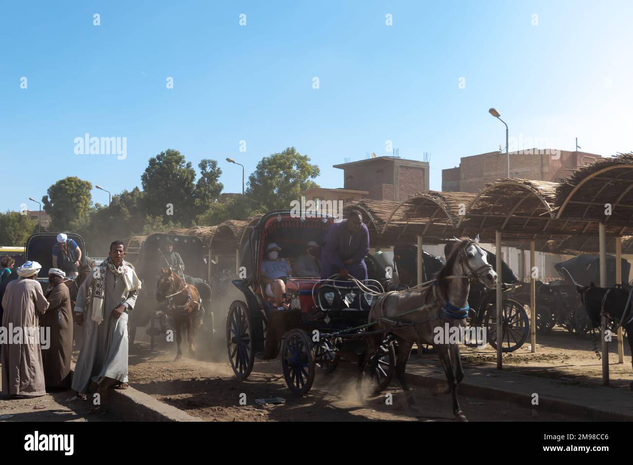 EDFU, ÉGYPTE - 28 décembre 2022. Scène de la ville pauvre et de la campagne cheval comme moyen de transport avec la poussière dans l'air beacuase du sable Banque D'Images