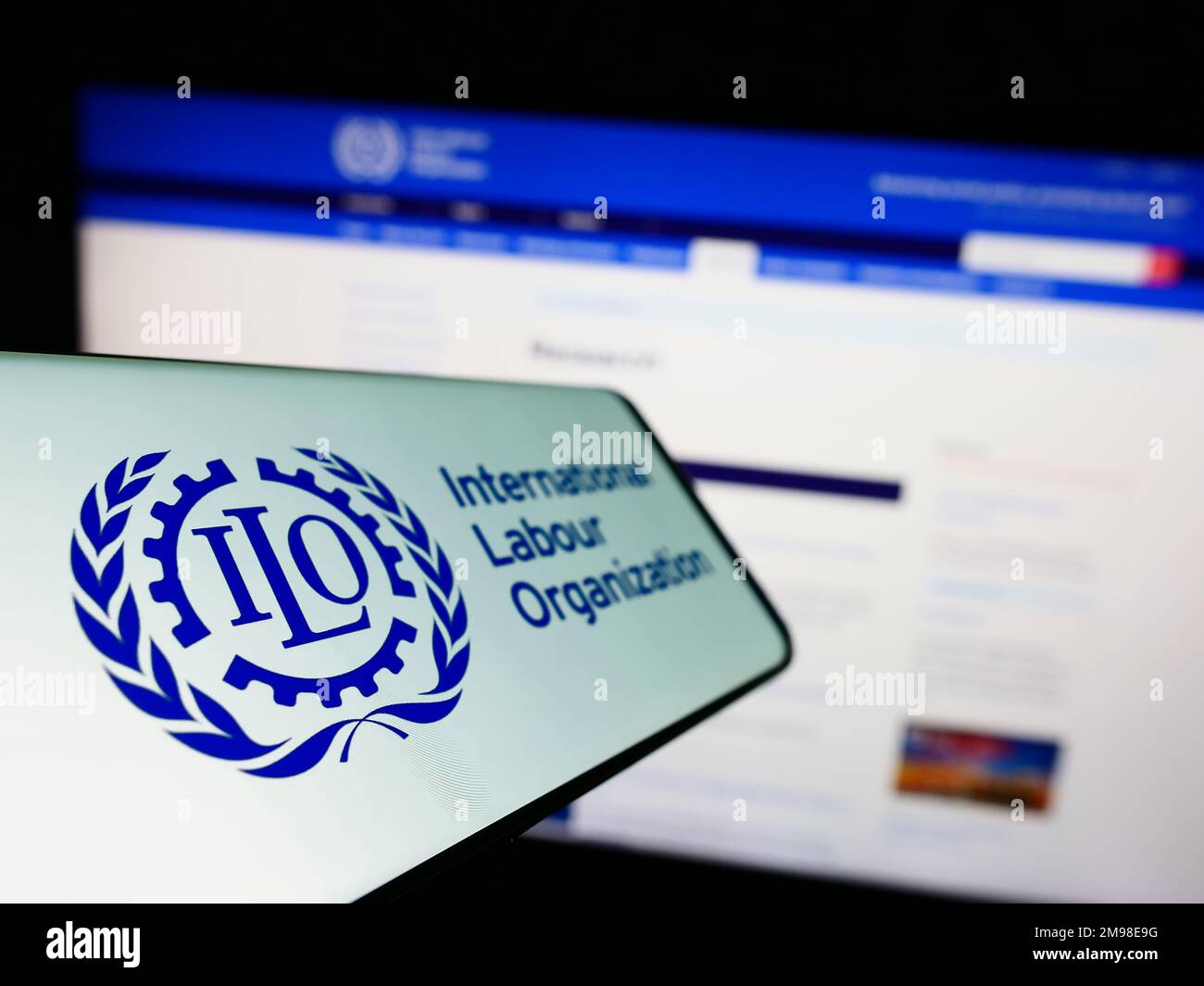 Smartphone avec logo de l'Organisation internationale du travail (OIT) de l'agence des Nations Unies sur l'écran devant le site Web. Mise au point à gauche de l'écran du téléphone. Banque D'Images