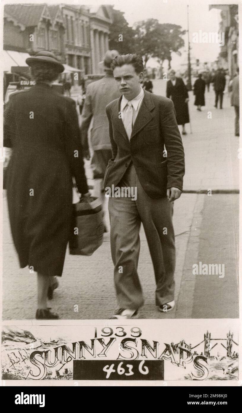Jeune homme élégant (notez le fantastique pantalon volumineux et les chaussures de style co-intimé - London Brogues) avec une expression plutôt sourde qui s'exprime volontairement le long du trottoir. Banque D'Images