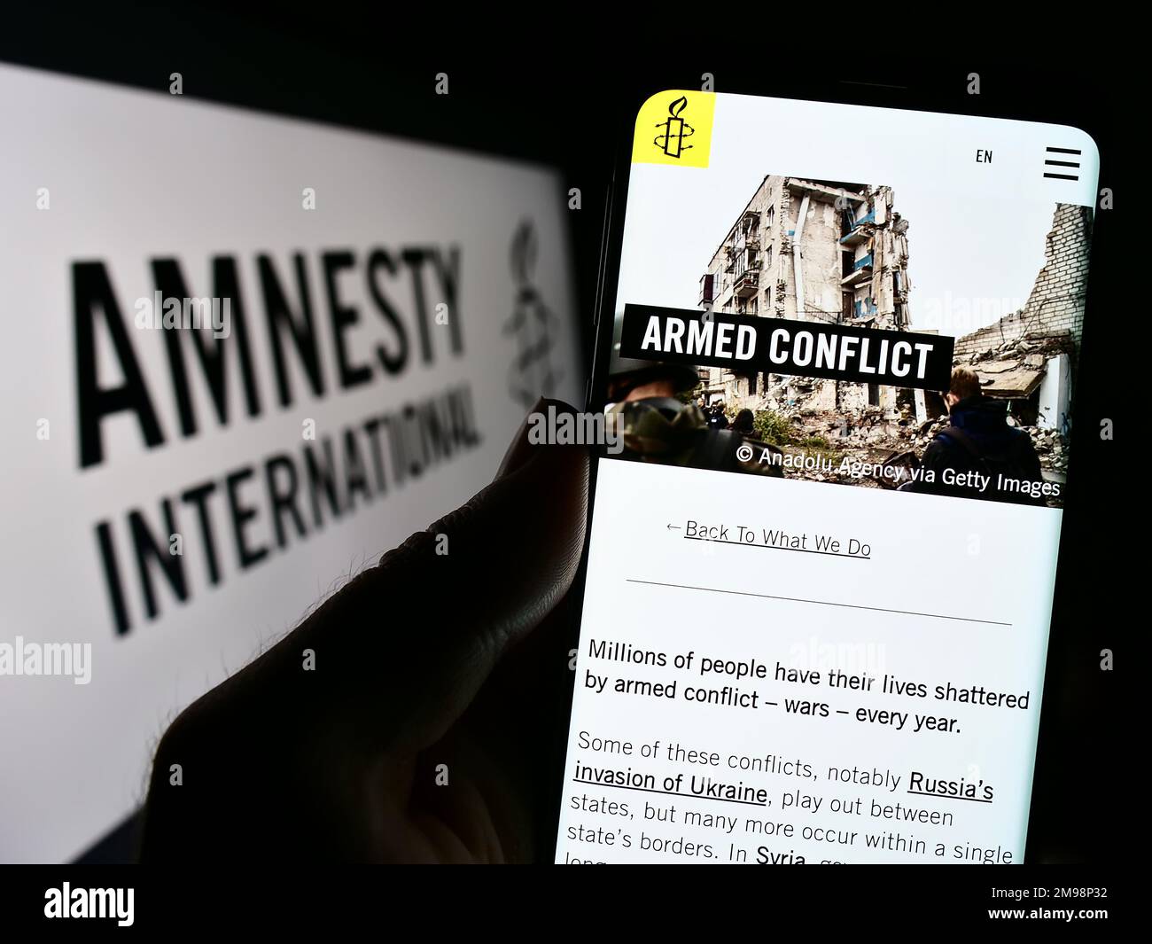 Personne tenant un smartphone avec une page Web de l'organisation des droits de l'homme Amnesty International à l'écran avec logo. Concentrez-vous sur le centre de l'écran du téléphone. Banque D'Images