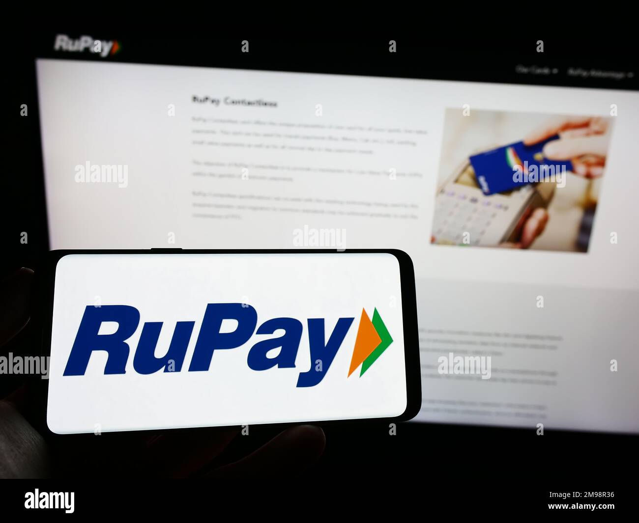 Personne tenant un téléphone portable avec logo du système de paiement indien RuPay à l'écran en face de la page Web. Mise au point sur l'affichage du téléphone. Banque D'Images