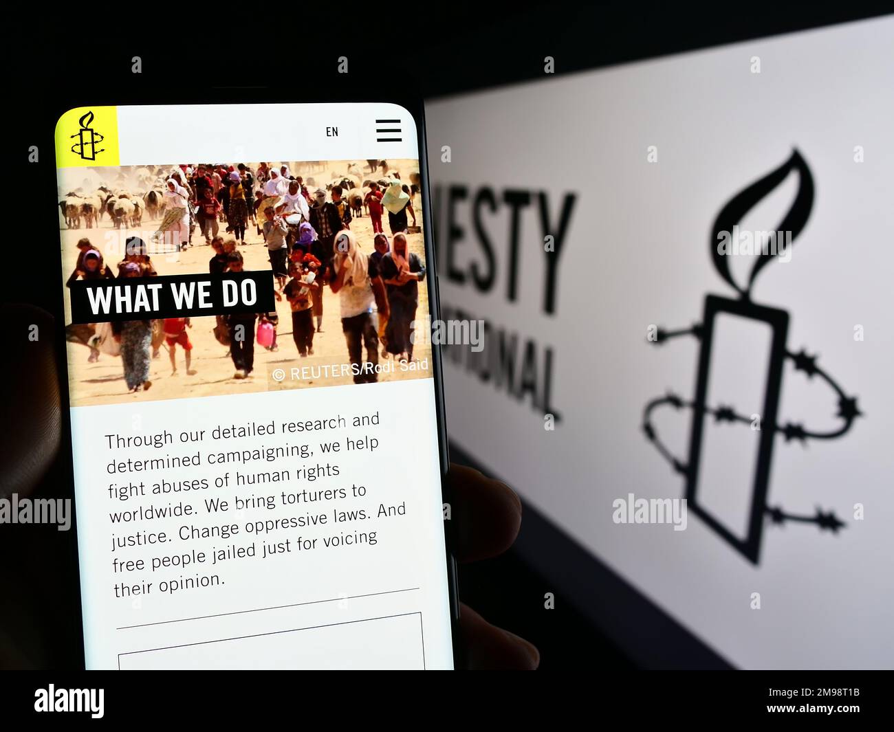 Personne tenant un téléphone portable avec une page web de l'organisation des droits de l'homme Amnesty International à l'écran avec logo. Concentrez-vous sur le centre de l'écran du téléphone. Banque D'Images