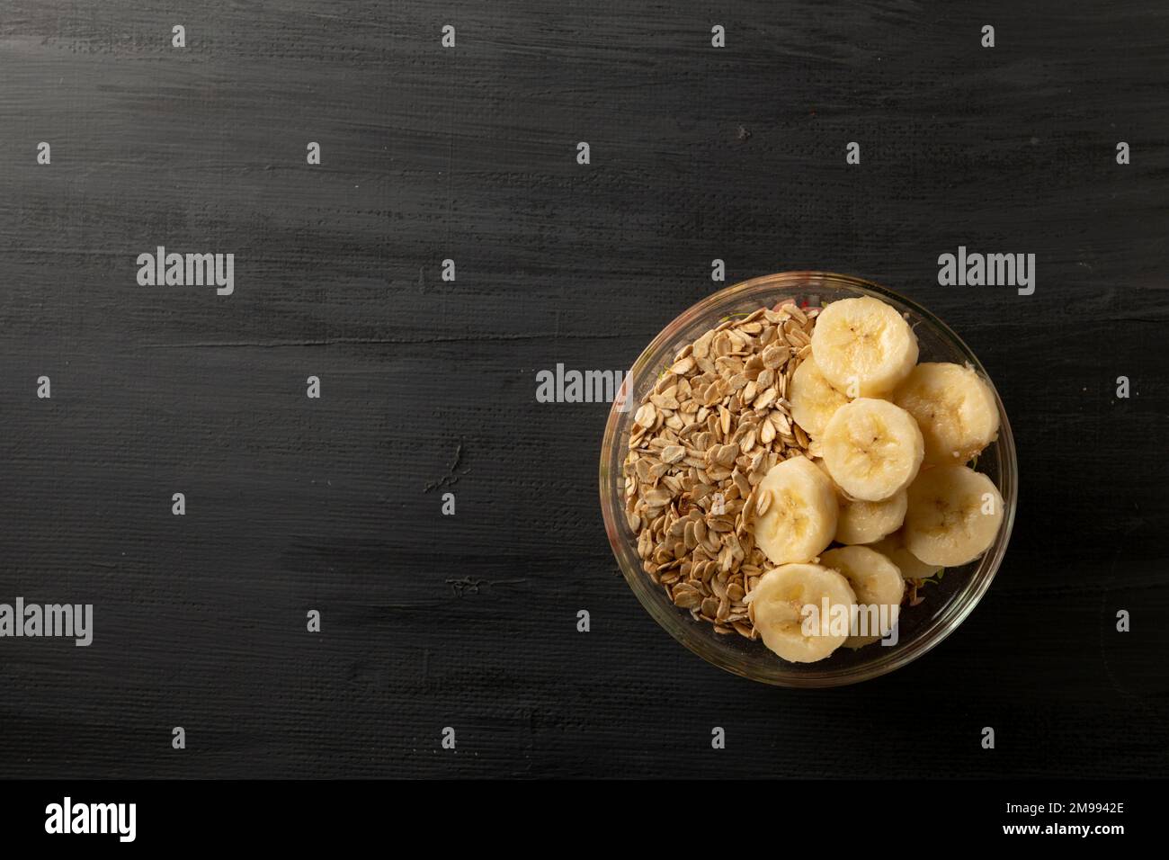 bol avec banane et avoine sur une base en bois gris avec espace de copie Banque D'Images