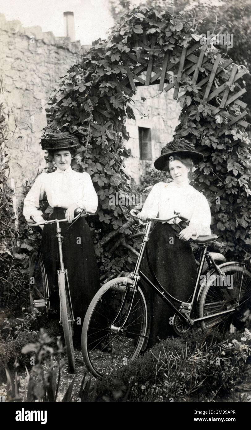 Deux femmes édouardiennes avec leurs vélos dans un jardin. Banque D'Images