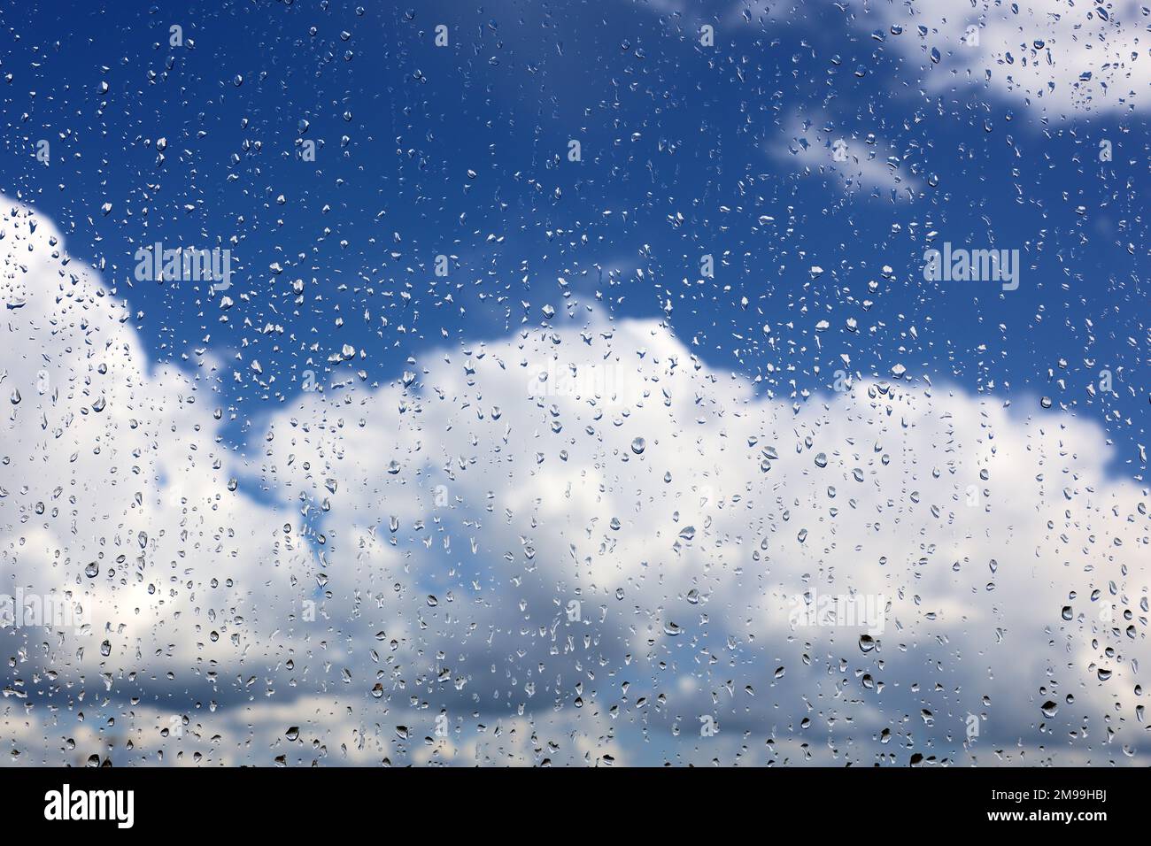 Gouttes de pluie sur la vitre sur fond flou du ciel avec des nuages blancs. De belles gouttes d'eau, le temps après la pluie Banque D'Images