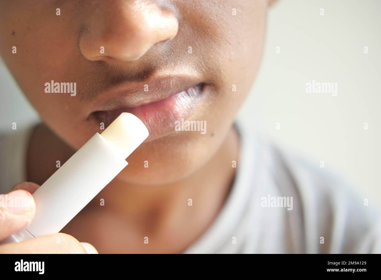 jeune homme appliquant un baume hydratant pour les lèvres sur les lèvres Banque D'Images