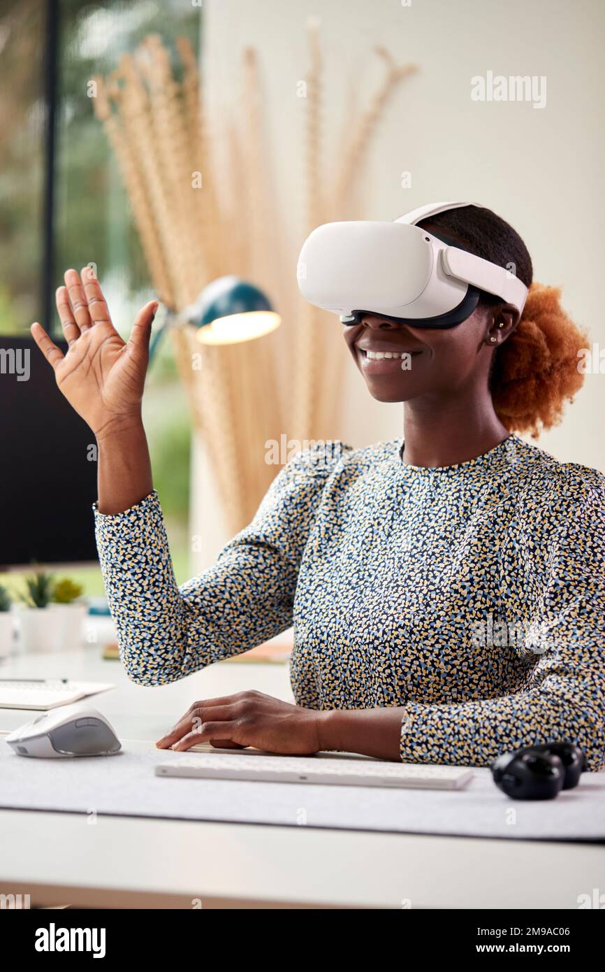 Femme travaillant à domicile assis au bureau en interaction avec la technologie AR ou VR Banque D'Images