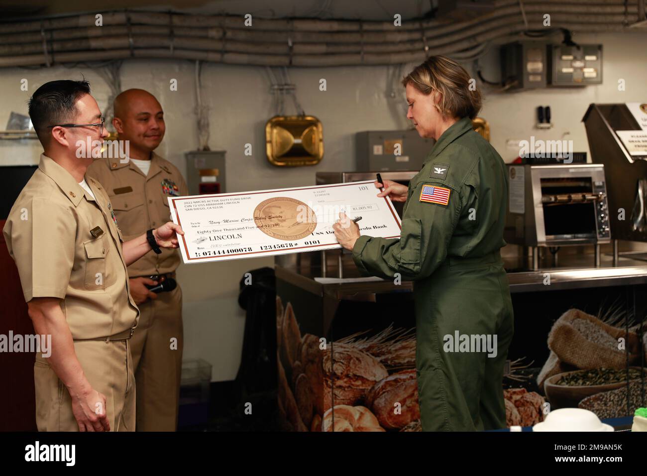 MER DES PHILIPPINES (15 mai 2022) le capitaine Amy Bauernschmidt, commandant du porte-avions de la classe Nimitz USS Abraham Lincoln (CVN 72), signe le chèque de la Marine-Marine corps relief Society. Abraham Lincoln Strike Group est en cours de déploiement prévu dans la zone d'exploitation de la flotte américaine 7th afin d'améliorer l'interopérabilité par le biais d'alliances et de partenariats tout en servant de force de réaction prête à l'emploi pour soutenir une région libre et ouverte d'Indo-Pacifique. Banque D'Images