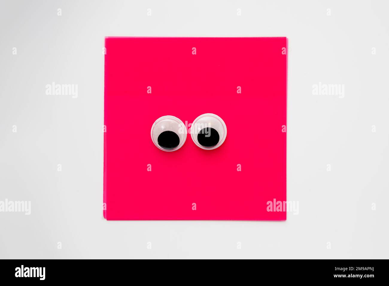 Paire de jolis yeux sur un bloc-notes carré rose isolé sur un fond blanc Banque D'Images