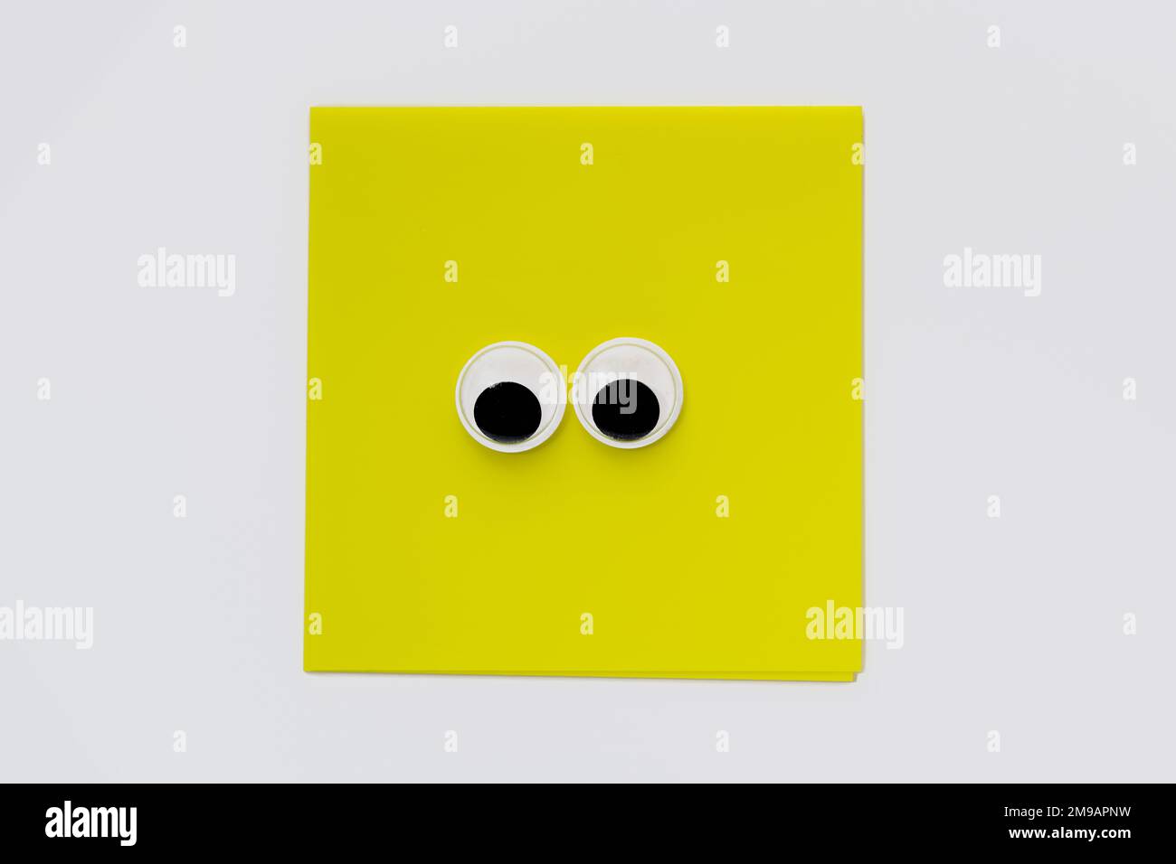 Paire de jolis yeux sur un bloc-notes carré jaune isolé sur un fond blanc Banque D'Images