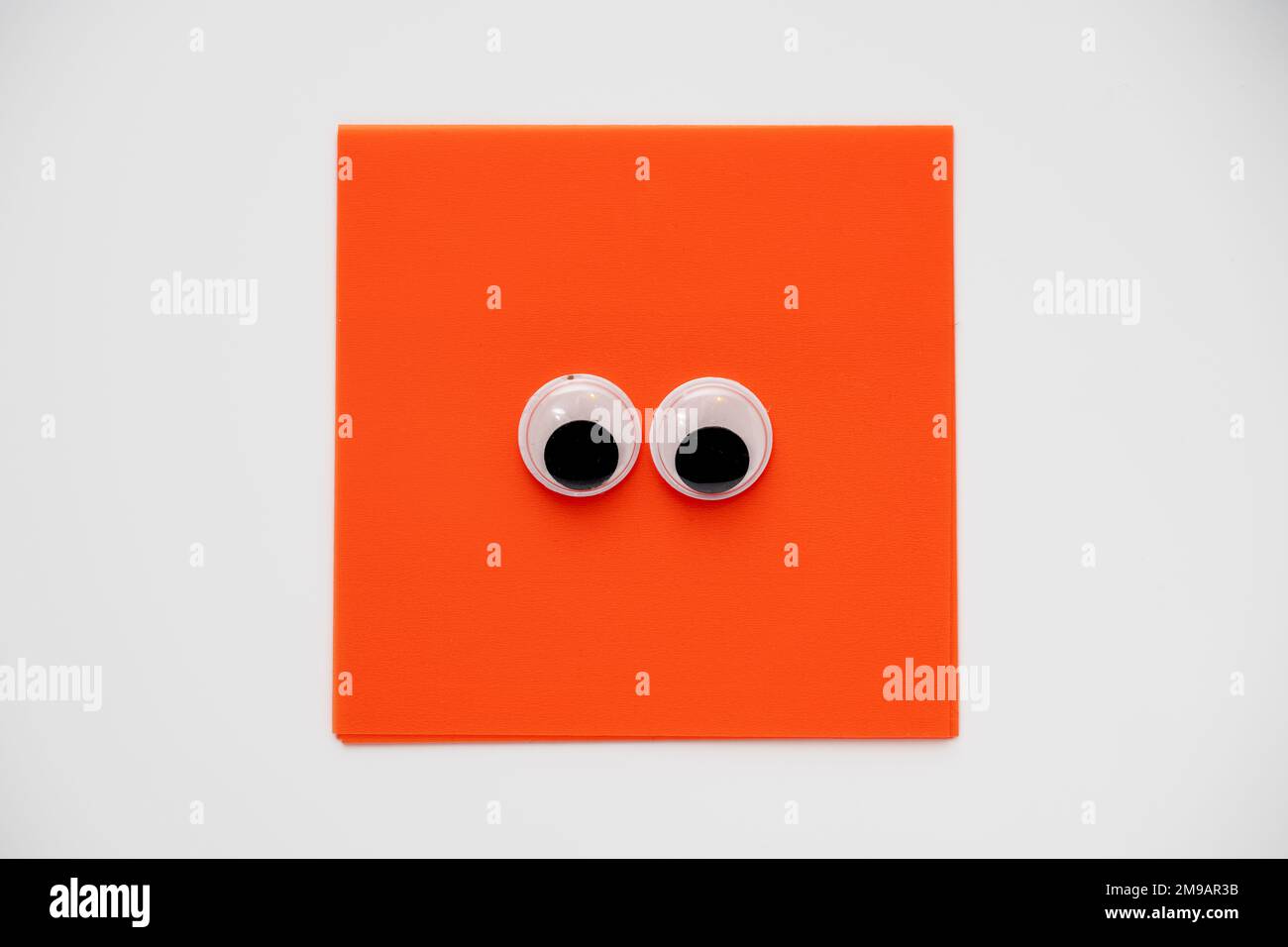 Paire de jolis yeux sur un bloc-notes carré orange isolé sur un fond blanc Banque D'Images