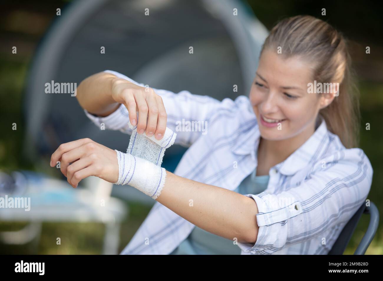 une femme bandage son propre poignet pendant les vacances de camping Banque D'Images