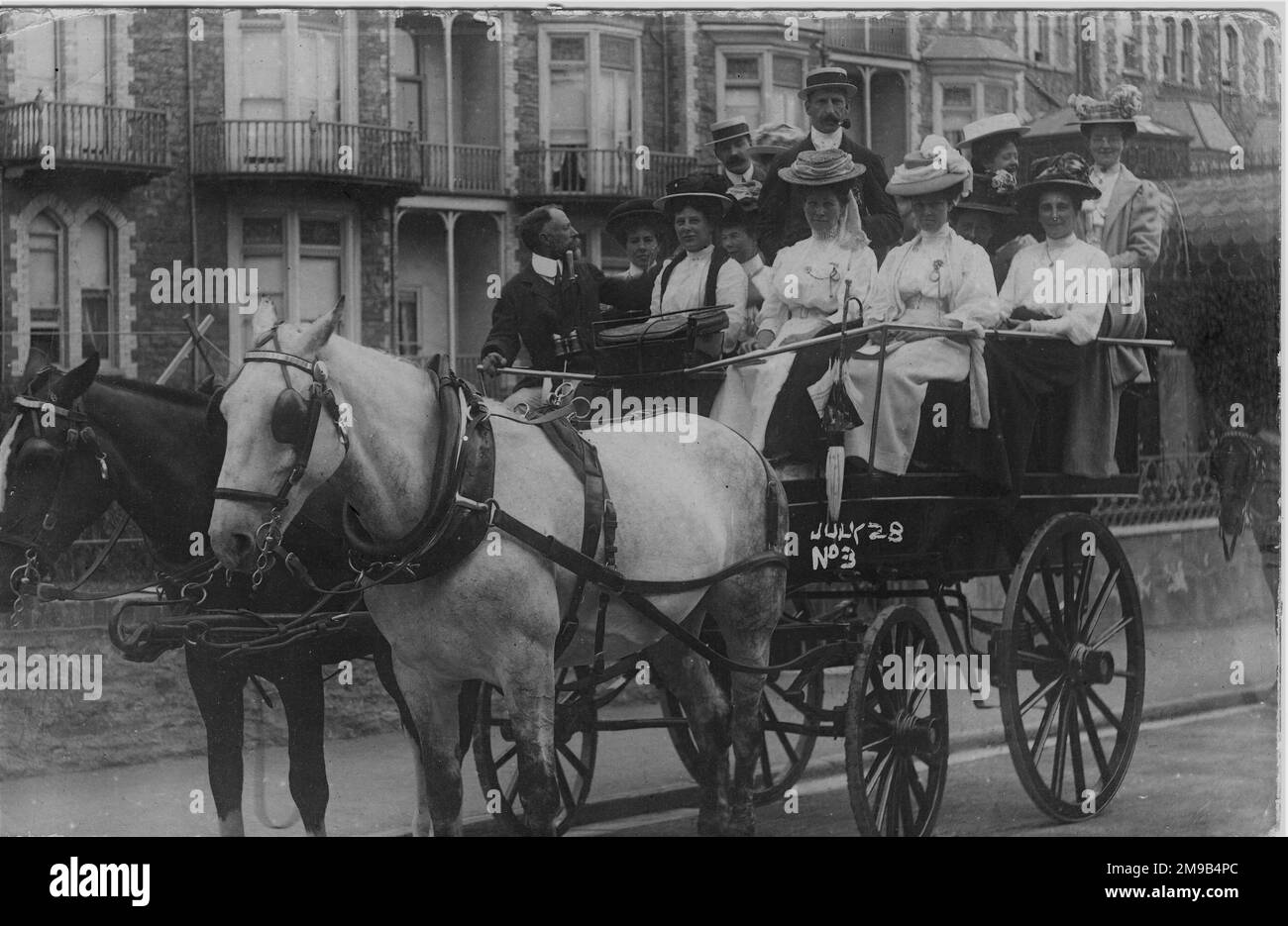 Deux chevaux, l'un noir et l'autre blanc, attendent patiemment tandis que le pilote intelligent regarde derrière pour voir si les autres voitures sont prêtes. Le message sur la carte postale l'identifie comme provenant de l'hôtel Cecil à Ilfracombe. La carte a été publiée seulement 2 jours après le voyage. Banque D'Images