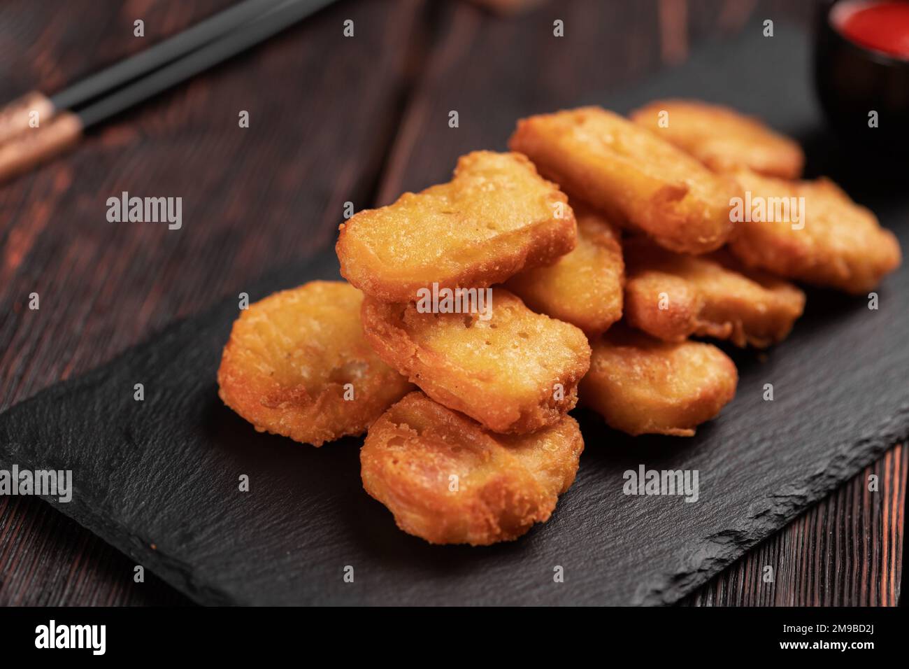 Morceaux de poulet frits sur un plateau de pierre avec baguettes - gros plan sur la nourriture asiatique Banque D'Images