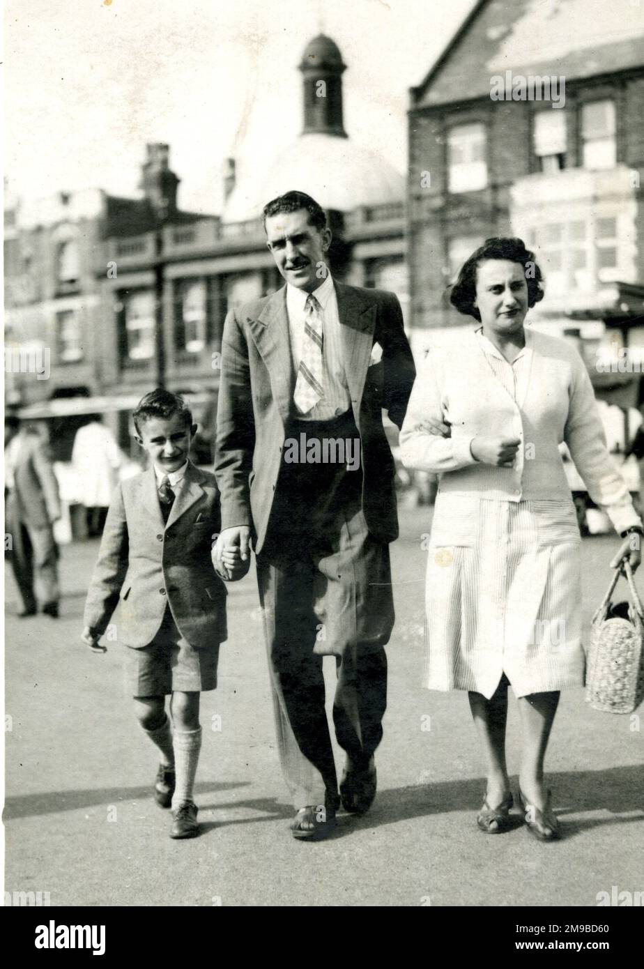 Famille de trois personnes marchant dans la rue Banque D'Images
