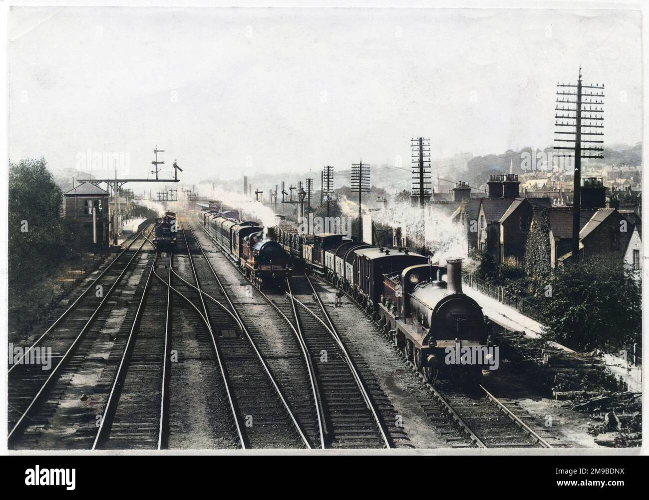 Un train de marchandises attend sur une voie pour laisser passer le train de voyageurs, tandis qu'un troisième train s'approche à travers la gare de Redhill, Surrey. Banque D'Images