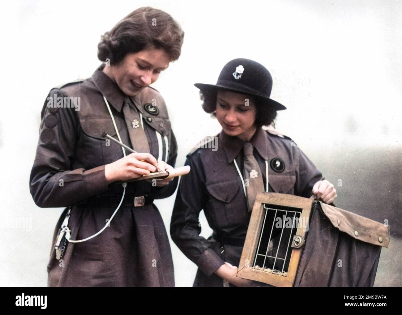 La princesse Elizabeth, chef de patrouille de la Buckingham Palace Company, envoie un message par pigeon de messagerie à Lady Baden Powell, au siège de Guide. C'était l'un des nombreux messages envoyés par les guides de filles partout dans le pays à l'occasion du "jour de pensée", qui marque l'anniversaire du regretté Lord Baden Powell. Fondateur des scouts, et sa femme.la princesse Margaret tient le conteneur de pigeon, tandis que la princesse Elizabeth écrit le message, à Windsor. Banque D'Images