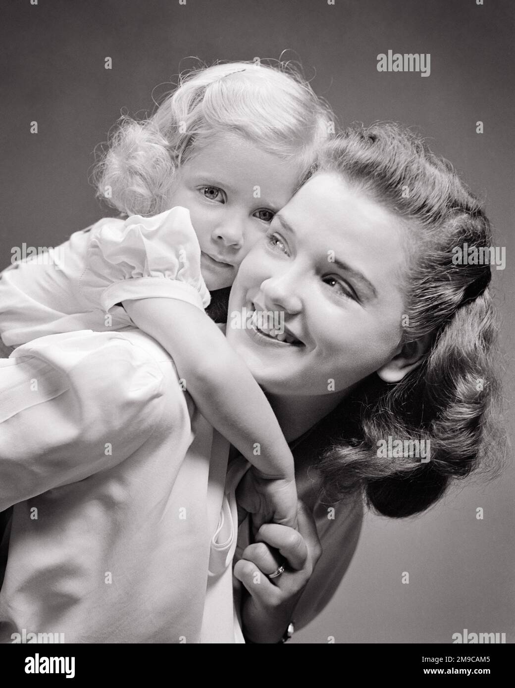 1940S FILLE BLONDE QUI MONTE SUR LES BRAS ARRIÈRE DE MAMAN AUTOUR DE SON COU MOM REGARDANT PAR-DESSUS SON ÉPAULE À LA FILLE QUI EST REGARDER LA CAMÉRA - J10568 HAR001 HARS 1 COMMUNICATION JUVÉNILE JEUNE ADULTE ÉQUILIBRE COU TRAVAIL D'ÉQUIPE HEUREUX FAMILLES JOIE STYLE DE VIE FEMMES STUDIO SHOT SAIN VIE VIE COPIE ESPACE FEMMES FILLES PERSONNES S'OCCUPANT B&W OEIL CONTACT BONHEUR TÊTE ET ÉPAULES GAIE BAS ANGLE FIERTÉ SOURIRES QUI CONNEXION JOYEUSE COOPÉRATION JEUNES MAMAN MAMANS PIGEGYBACK TOGETHNESS JEUNE FEMME ADULTE NOIR ET BLANC RACE BLANCHE HAR001 DÉMODÉE Banque D'Images