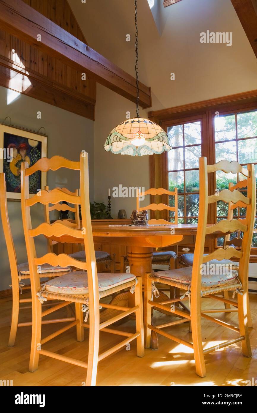 Table de petit déjeuner ronde en bois avec chaises à dossier haut dans la salle de cuisine à l'intérieur de la maison en rondins de style Canadiana. Banque D'Images