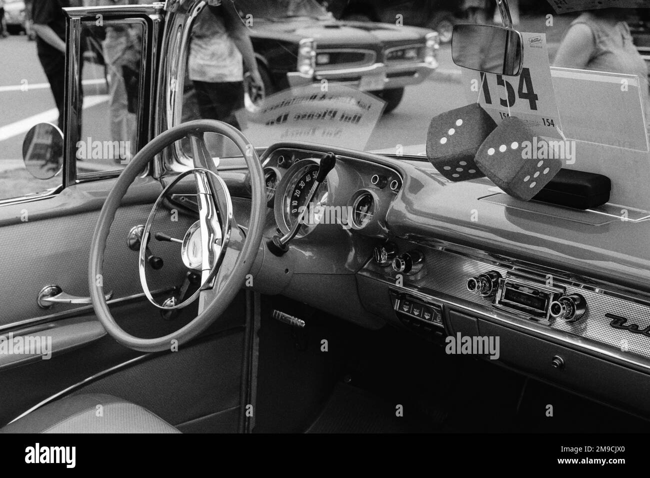 Les dés sont suspendus au miroir au-dessus du tableau de bord d'un véhicule d'époque Chevrolet Belair lors d'un salon automobile dans l'Essex, au Massachusetts. L'image a été prise en noir et Banque D'Images