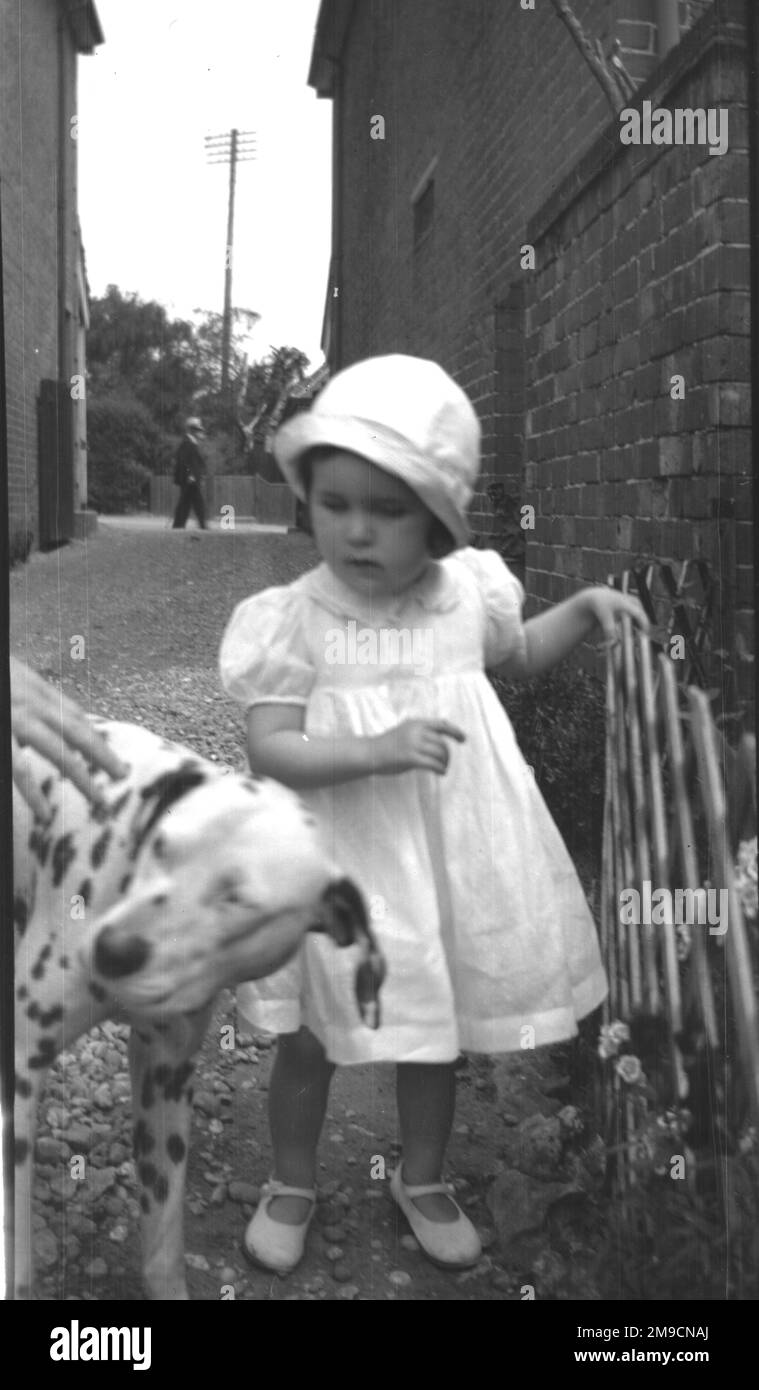 Une petite fille dans une rue avec un chien dalmate Banque D'Images
