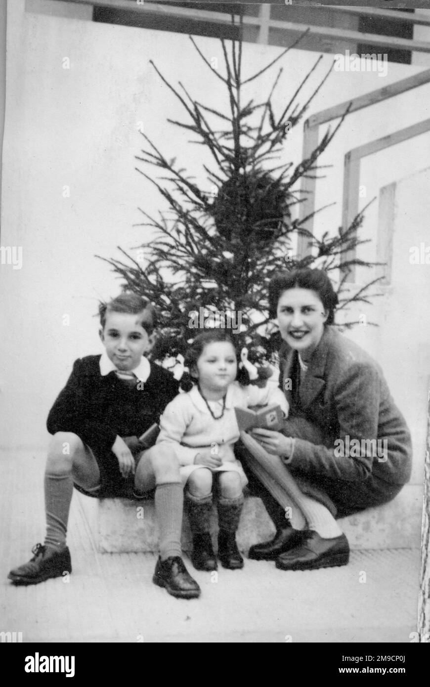 Mère, fils et fille posent devant leur arbre de Noël. Banque D'Images