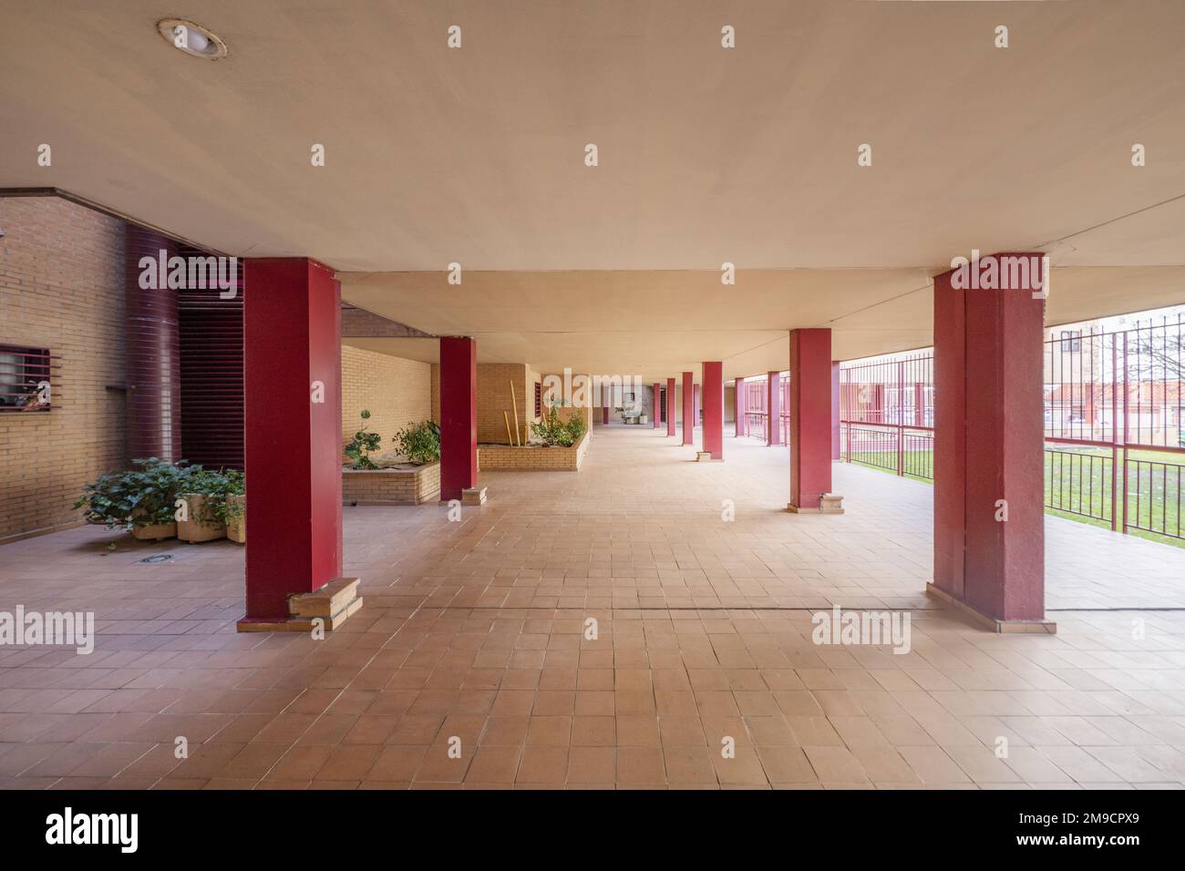 Les parties communes d'un bâtiment résidentiel avec des piliers peints en rouge et de petits sols carrelés en argile Banque D'Images