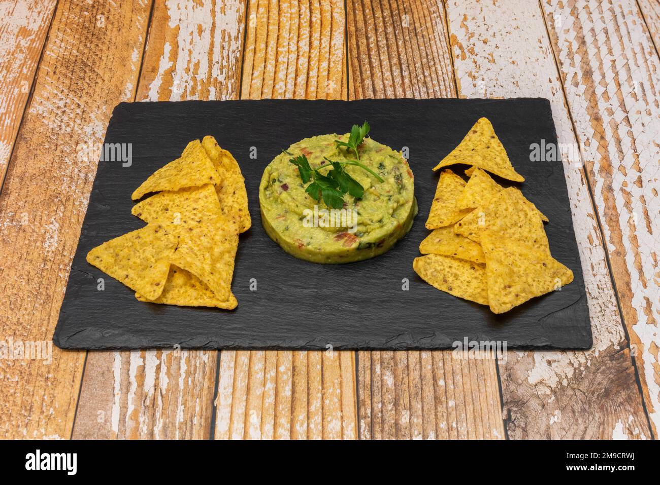 Un plateau en ardoise avec un hors-d'œuvre de guacamole mexicain et des chips de tortilla de maïs Banque D'Images