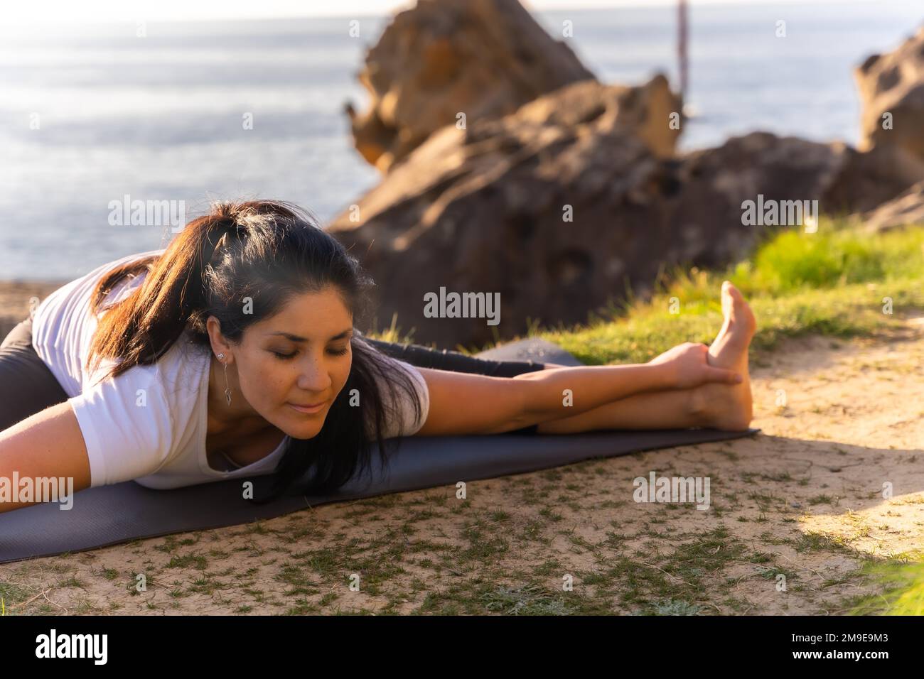 Une femme faisant des exercices de yoga dans la nature au bord de la mer, faisant des étirements Banque D'Images